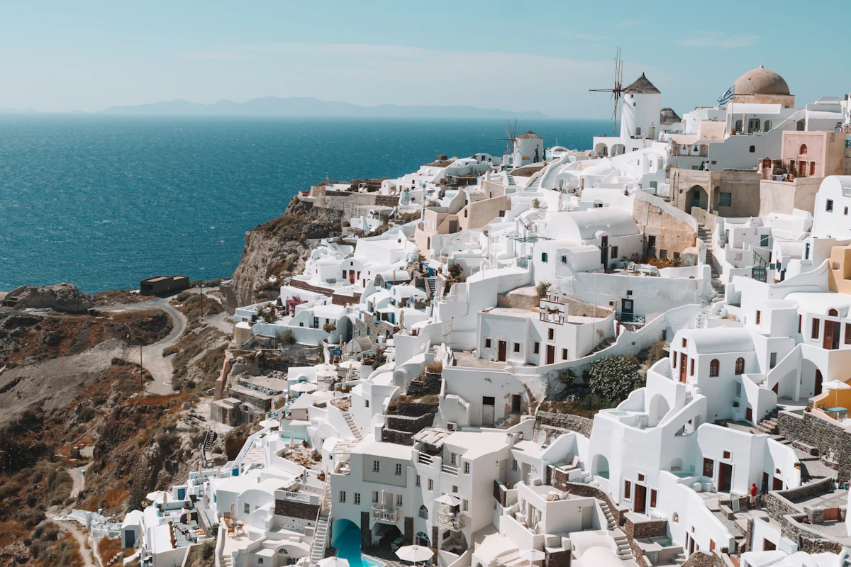 White hillside houses descending to a deep blue Greek bay